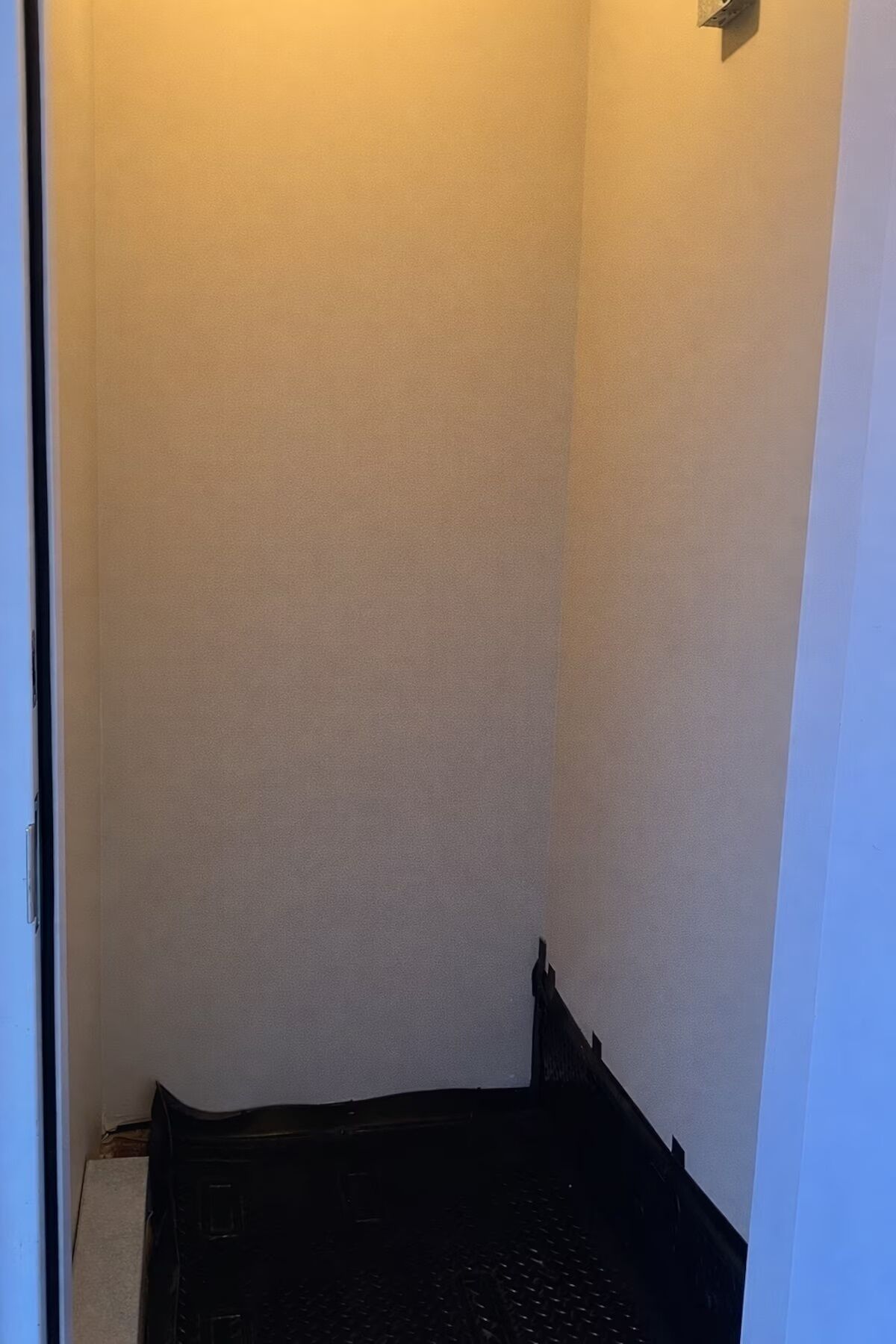 Un coin de pièce avec un mur à texture et un plancher foncé.