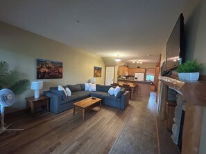 A living room with a sectional sofa, a coffee table, a TV, and a fireplace.