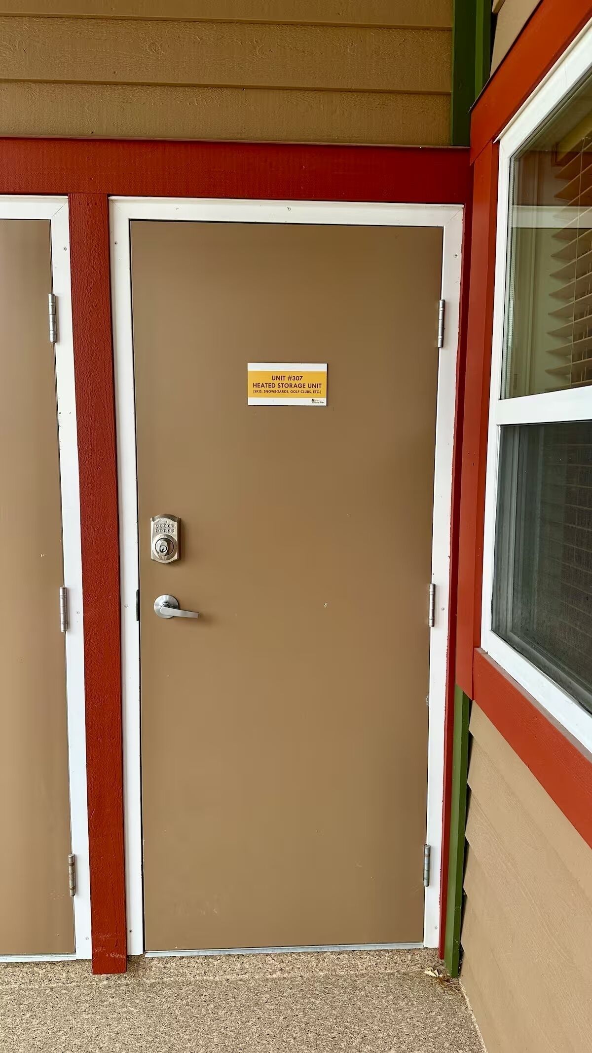 Une porte marron avec une pancarte indiquant qu’il s’agit d’un espace de stockage chauffé, un clavier pour ouvrir la porte et une poignée.