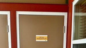 A brown door with a sign indicating it is a heated storage unit, a keypad lock, and a handle. - Ski & Golf Getaway Suite - private hot tub - 2 bed (Kimberley)
