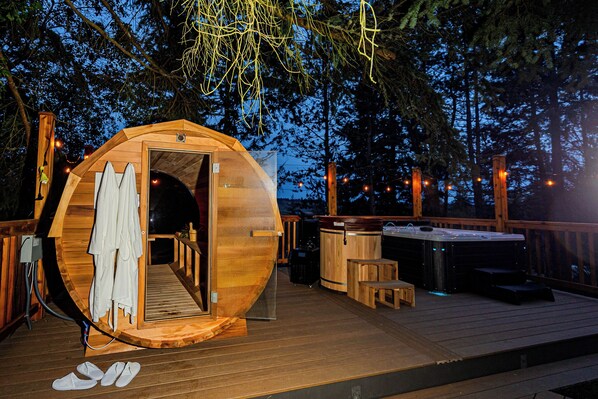 A wooden cabin with an open door, a hot tub, and a deck.