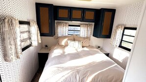 A compact bedroom with a bed, curtains, and a window.