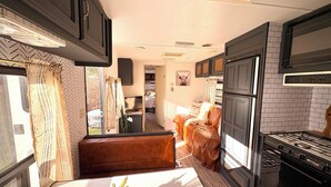 A compact RV interior with a kitchenette, a dining area, and a living space.
