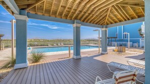 A covered outdoor area with a pool, wooden deck, and seating.