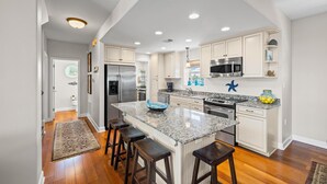 A modern kitchen with white cabinetry, granite countertops, and stainless steel appliances.