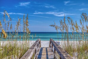 A wooden boardwalk leading to a beach with clear blue water and tall grasses. - Portside Villas Perfect 10- Gulf Side w/Gulf Views- Steps to Beach + Pool (Pensacola Beach)