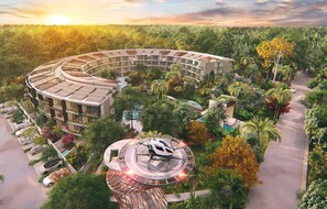 Een modern hotel met een rond ontwerp, omringd door weelderig groen en een parkeerplaats.