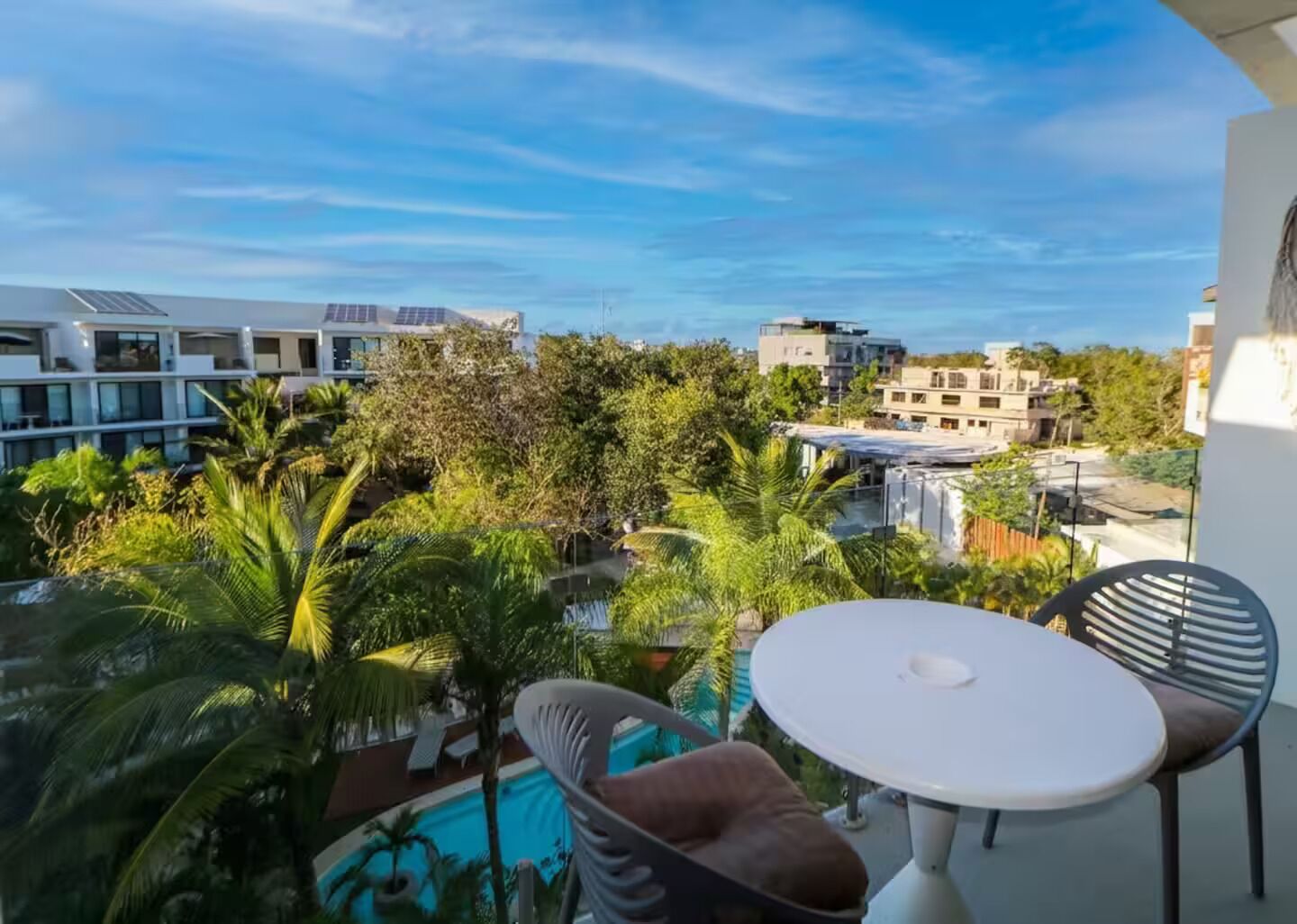 Un balcon avec une piscine, des chaises et une table.