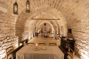 An interior with stone walls, a table with a candle, and a bench. - Masseria Le Cerase – An Apulian Masseria for 10 People (Conversano)