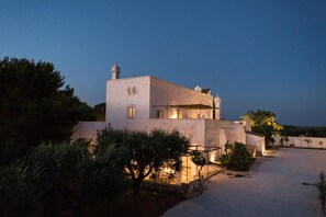 A modern two-story building with a flat roof, a visible chimney, and a well-lit entrance. - Masseria Le Cerase – An Apulian Masseria for 10 People (Conversano)