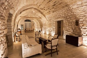 Una habitación con paredes de piedra, un sofá, sillas y una mesa.