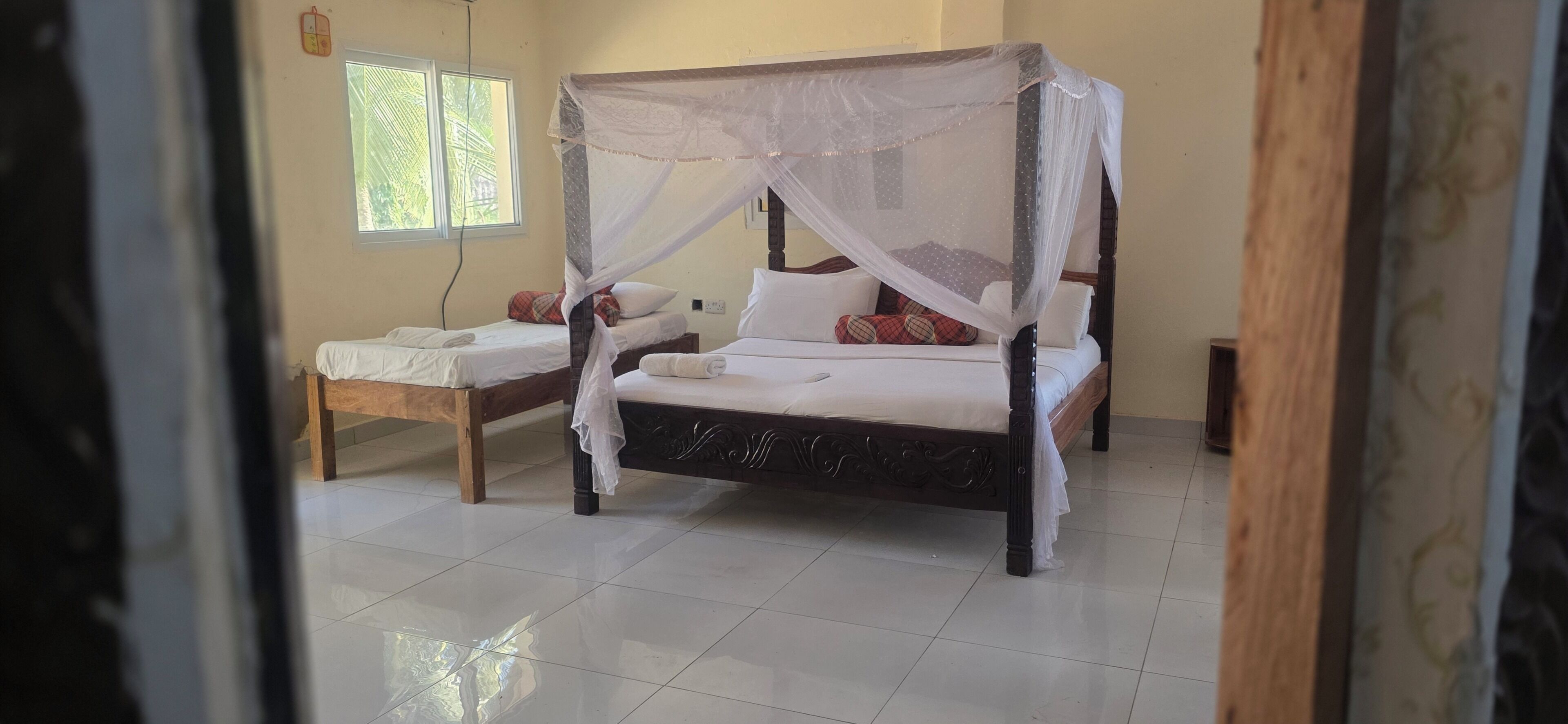 A room with a four-poster bed, a single bed, and a bench.