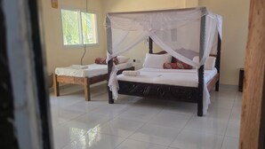 A room with two beds, one with a canopy and another without, both with white linens. - Luxurious 4-bedroom Holiday House With Pool Access in Diani Beach (Diani Beach)