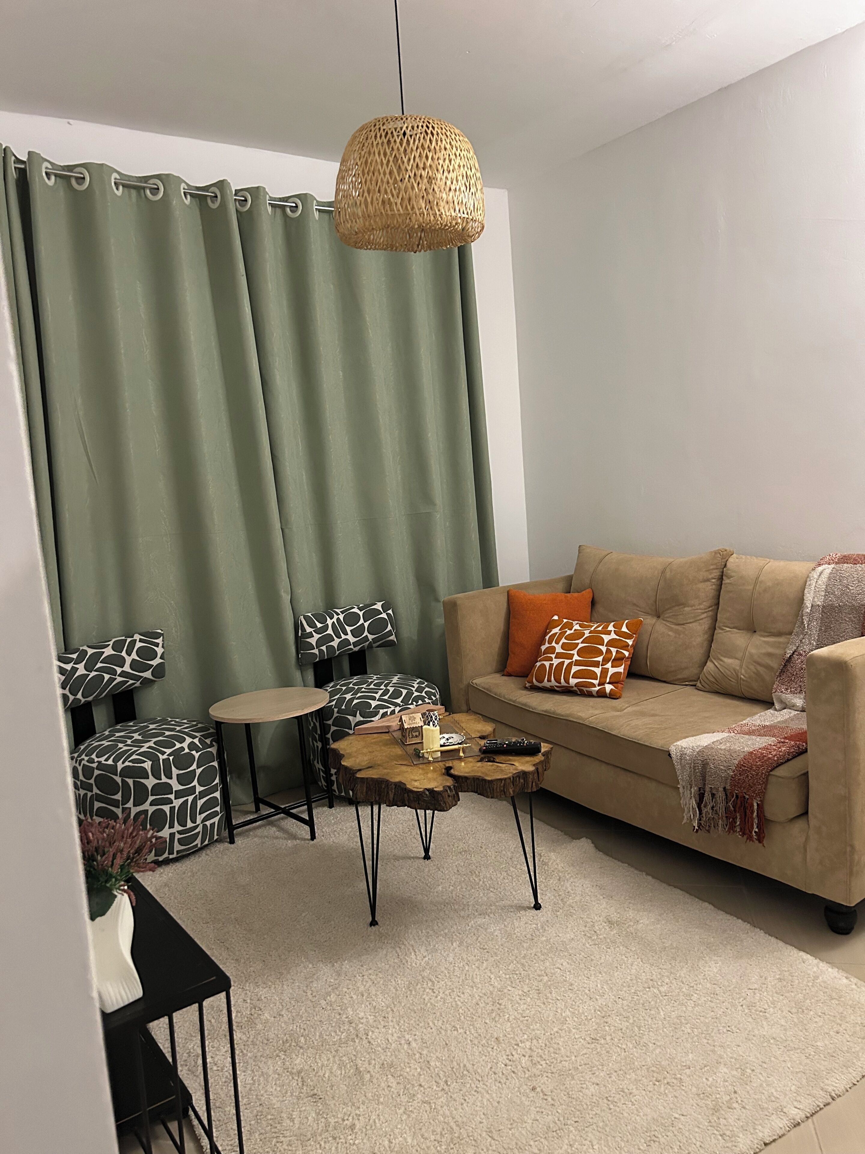 Ein Wohnzimmer mit einer Couch, einem Couchtisch, einem Beistelltisch, einem Sessel, einem kleinen runden Tisch und einer Pendelleuchte.
