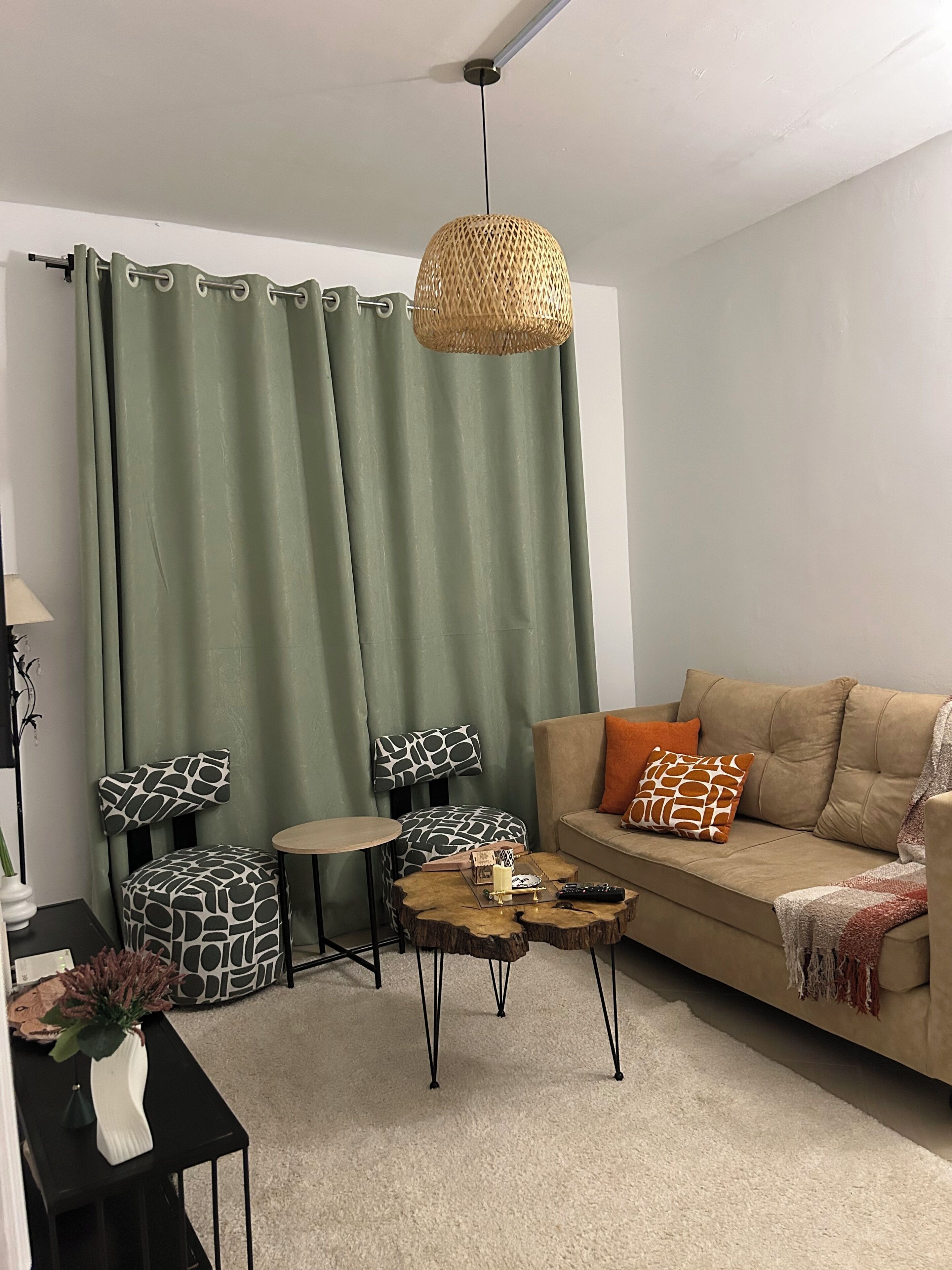 A living room with a sofa, a coffee table, a side table, a small round table, and a chair with a patterned cushion.