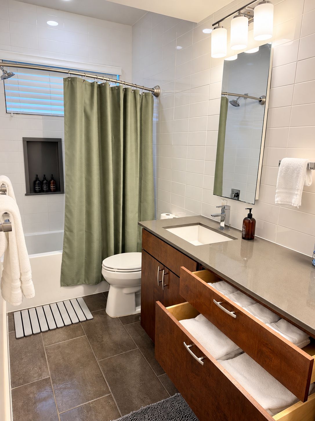 A modern bathroom with a shower, toilet, vanity, and a mirror.