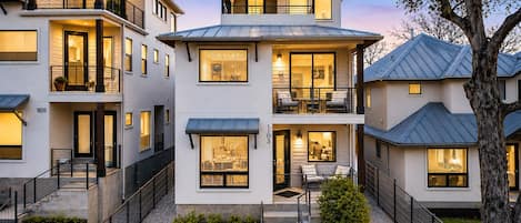 A multi-story residential building with a balcony, a staircase, and a small garden area.