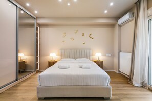 A bedroom with a large bed, bedside lamps, a wardrobe, a radiator, and a window with curtains. - Acropolis Propylaea Apartment by A&A Residencies  (Athens)