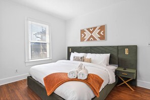 A bedroom with a bed, a nightstand, a wall art piece, and a window with blinds. - Atlanta Basecamp | Pet-Friendly | Walkable (Atlanta)