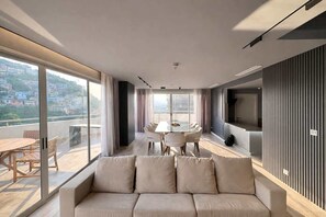 A modern living room with a sofa, a dining table with chairs, and a TV on the wall. - Stylish Loft, Balcony and City Views with Parking (Guayaquil)