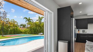 A modern kitchen with dark cabinetry, a built-in oven, and a small refrigerator. - Villa Solara | Pool · Cinema · Basketball Court  (North Miami Beach)