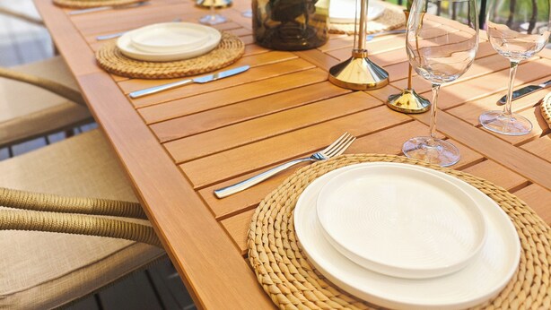 A wooden dining table set with plates, cutlery, and candles, with a vase of flowers in the center. - Stylish 5BR Entire House Near Vancouver Sleeps 8 Free Parking with AC (Burnaby)