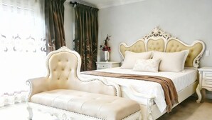 A bedroom with a large bed, a chaise lounge, a nightstand, and a vase with flowers. - Stylish 5BR Entire House Near Vancouver Sleeps 8 Free Parking with AC (Burnaby)