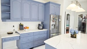 A kitchen with blue cabinets, a white countertop, a stainless steel refrigerator, and a coffee maker. - Stylish 5BR Entire House Near Vancouver Sleeps 8 Free Parking with AC (Burnaby)