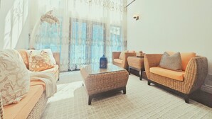 A living room with wicker furniture, a glass coffee table, and a view through large windows. - Stylish 5BR Entire House Near Vancouver Sleeps 8 Free Parking with AC (Burnaby)