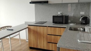 Une cuisine moderne équipée d’un four à micro-ondes, d’une machine à café et de meubles de rangement en bois.