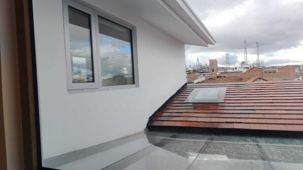 A rooftop terrace with a view of a cityscape, including a church and residential buildings. - ART DECO CUENCA (Cuenca)