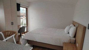A bedroom with a bed, a desk, a chair, and a wardrobe. - ART DECO CUENCA (Cuenca)