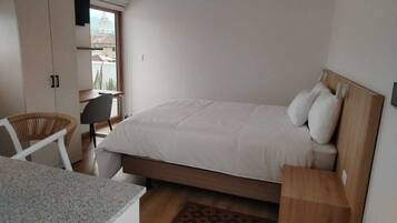 A bedroom with a bed, a desk, a chair, and a wardrobe.