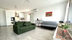 A modern living room with a green sofa, a grey sofa, a kitchen area, and a dining table. - Spring House - The porch .... For a relaxing vacation (Valeggio sul Mincio)