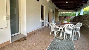 A covered patio with white chairs, a table with a flower vase, and a stone wall. - Spring House - The porch .... For a relaxing vacation (Valeggio sul Mincio)