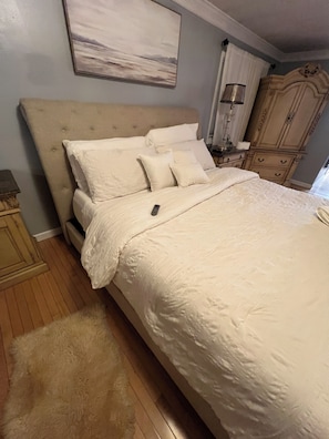 Une chambre à coucher avec un grand lit, une tête de lit, une table de chevet, une lampe et une armoire.