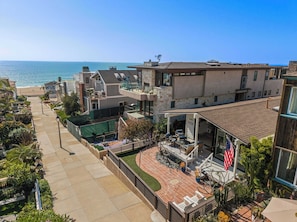 A residential area with a patio, a view of the ocean, and a house with a balcony. - Steps to Sand | Beach Home (Manhattan Beach)