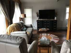 Un salon comprenant un canapé, une table basse, un téléviseur et un meuble.