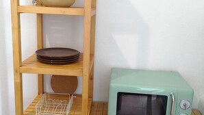 Een houten wandplank met kommen, borden en een magnetron.