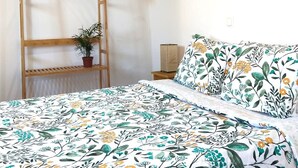 Een slaapkamer met een bed, een houten plank met een plant en een kledingroede.