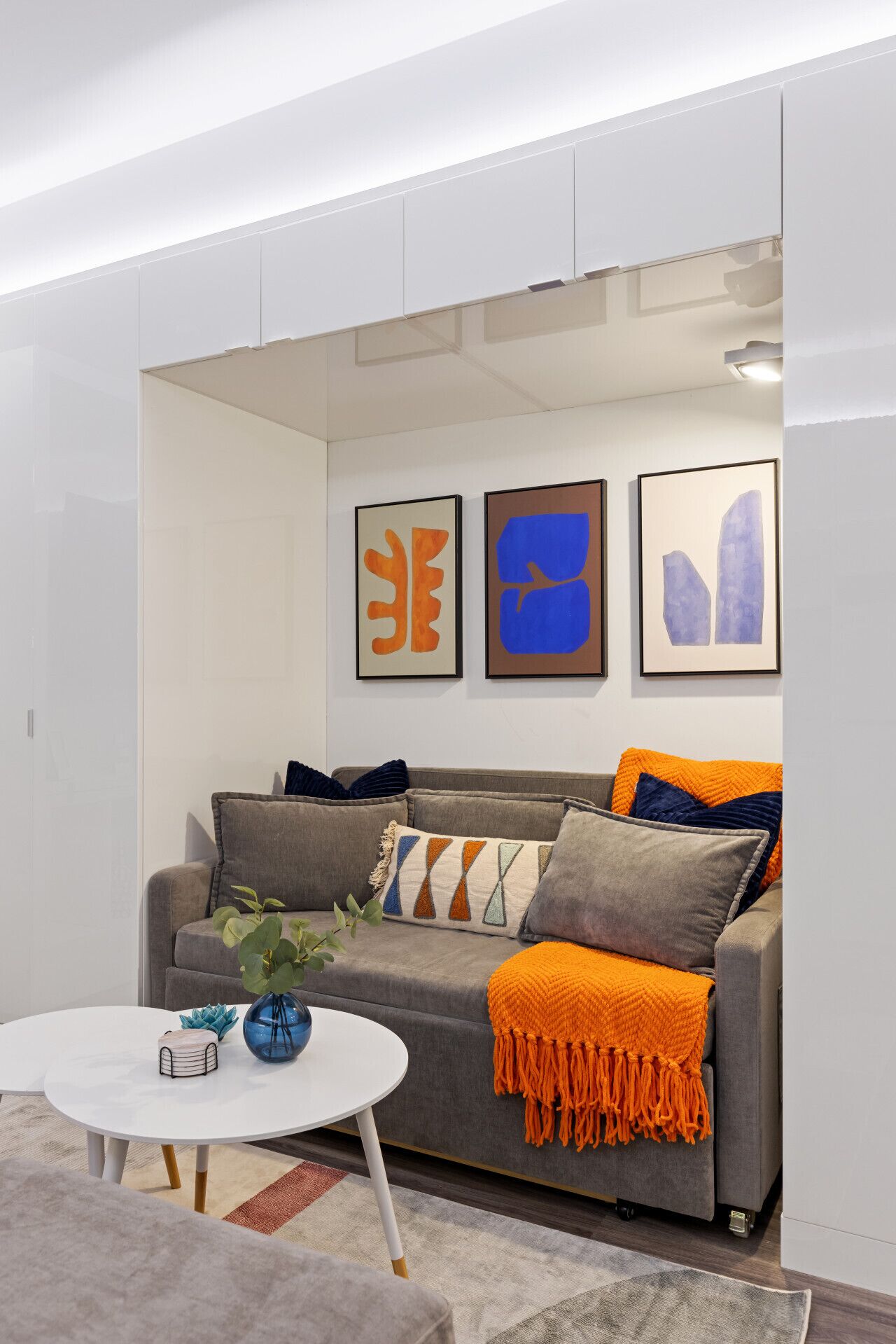 A modern living room with a grey sofa, a white coffee table, and abstract art on the wall.