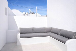 Une pièce blanche avec un canapé gris et un mur blanc.