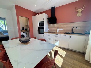 Una cocina moderna con armarios blancos, una campana extractora negra y un protector contra salpicaduras de madera.