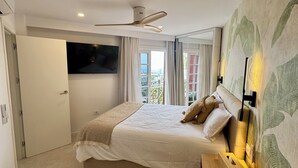 Un dormitorio moderno con una cama, televisor, ventilador de techo y vistas al exterior.
