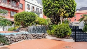 Un patio con una pequeña cascada, una piscina y un muro de piedra.