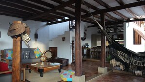 Amplia sala de estar con techo de madera, una hamaca, un sofá y una escalera que conduce a un nivel superior.