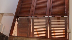 Una habitación con techo inclinado, vigas de madera, tragaluz y suelo de baldosas.