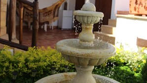 Una fuente de piedra con agua brotando de la parte superior, rodeada de follaje.