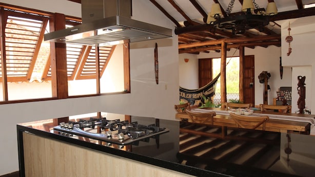 Una cocina con estufa a gas, vigas de madera y una hamaca.