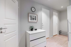 A hallway with white doors, a white dresser with drawers, a clock, and a framed picture on the wall. - Roof Terrace 3BR - Unesco Bryggen and Floien (Bergen)